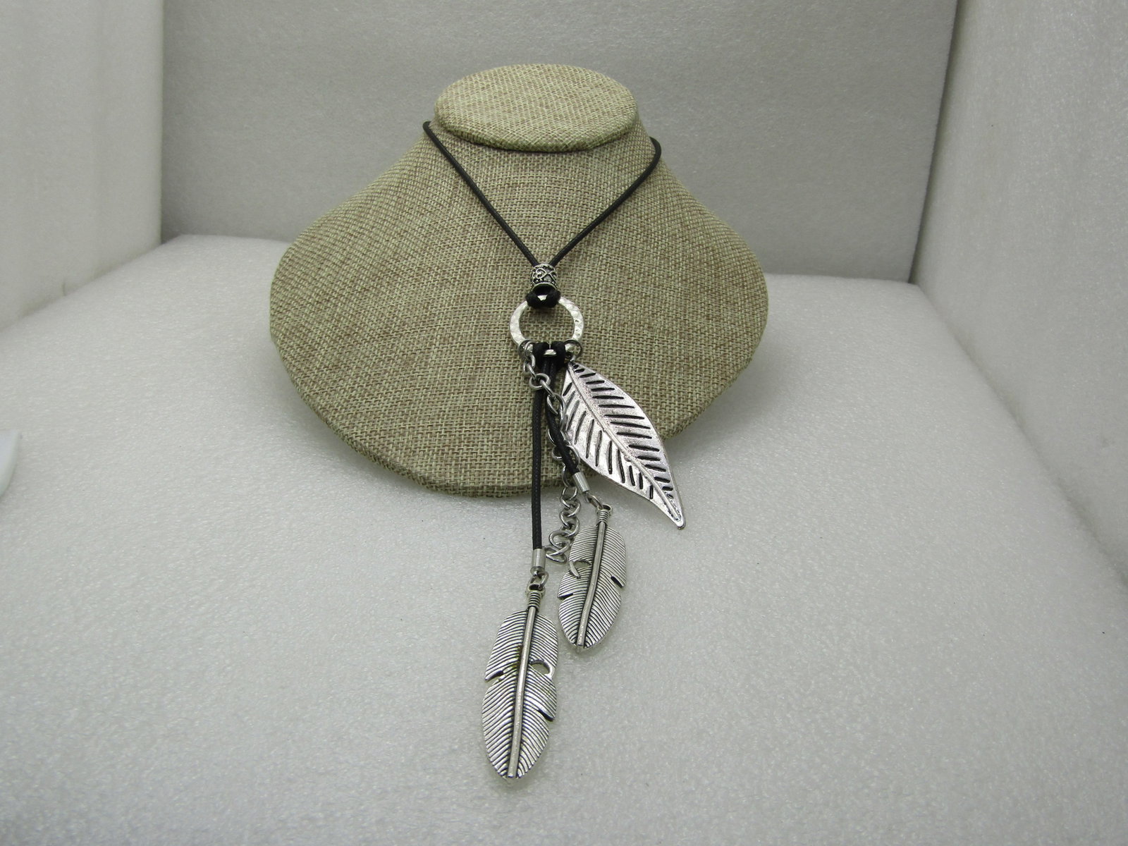 Silver Tone Dangling Feather Necklace, 26", Black Round Cord NL: Title: Silver Tone Dangling Feather Necklace, 26", Black Round Cord NL Description: Silver Tone Dangling Feather Necklace, 26", Black Round Cord. Three silver tone feathers with black ashed accents in