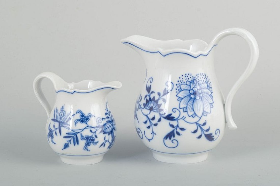Meissen, Germany. Two organically shaped blue Onion Pattern porcelain creamers. Early 20th century.: Meissen blue onion Two creamers, early 20th century. Organically shaped porcelain creamers with white glaze and hand-painted blue floral decoration in underglaze. Classic scalloped rim and curved hand