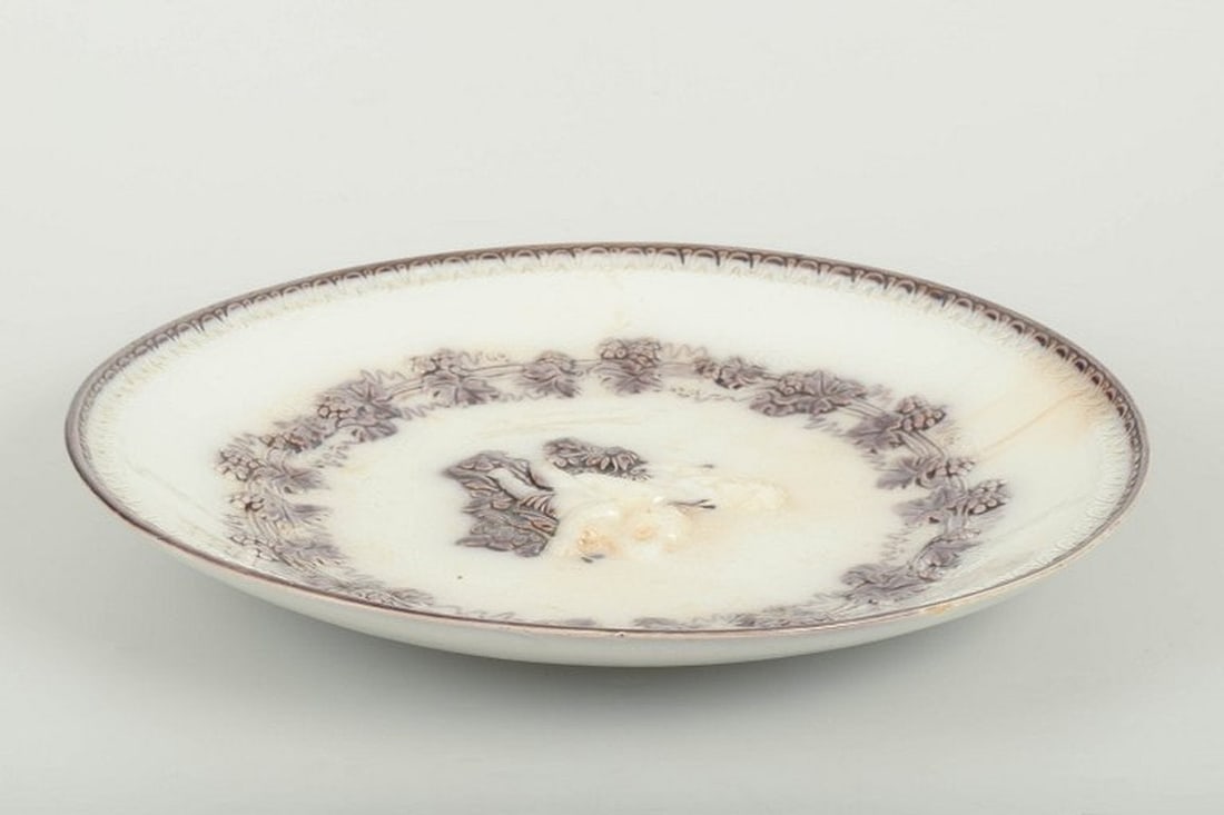 Gefle, Sweden. 'Mullbär' faience plate decorated with putti figures. Ca. 1880/90s.: Gefle Plate “Mullbär” with putti figures, c. 1880/90s. Round faience plate with relief decoration and transfer-printed vine motif in brown tone, centrally decorated with putti figures (cherub