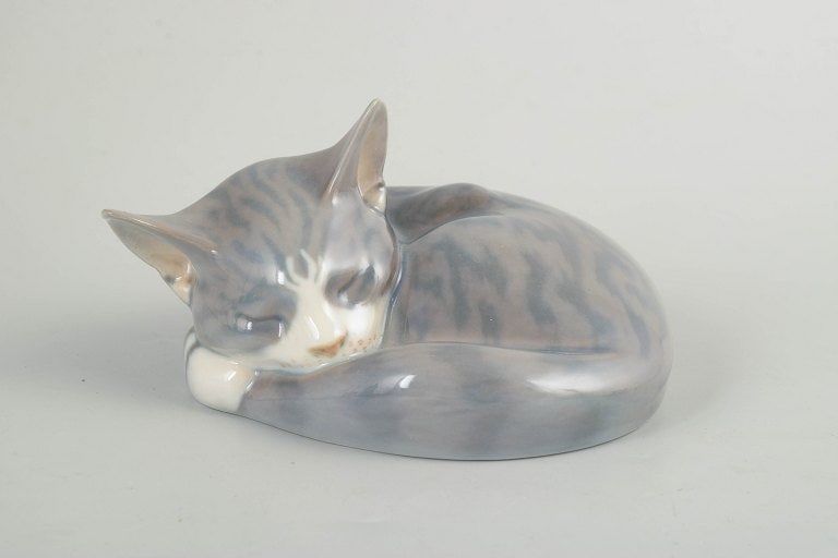 Royal Copenhagen, Denmark. Porcelain figurine depicting a curled, sleeping cat in grey and white: Royal Copenhagen, sleeping cat figurine. Porcelain figurine depicting a curled, sleeping cat, modelled with soft lines and finished in a subtle grey and white glaze with delicate tonal variations.