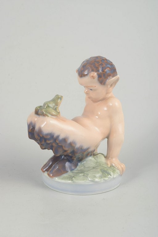 Royal Copenhagen, Denmark. Porcelain faun figurine with pastel colouring. Approx. 1980s.: Royal Copenhagen, faun figurine. Porcelain figurine depicting a faun and frog seated on a base, modelled with soft, naturalistic forms and subtle pastel colouring. Model 1713. Origin: Denmark.