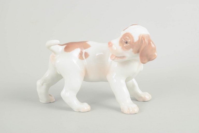 Bing & Grøndahl, Denmark. Porcelain puppy figurine in light brown and cream tones. Approx. 1920s.: Bing & Grøndahl, puppy figurine. Naturalistically modelled porcelain figurine depicting a standing puppy with soft forms and hand-painted decoration in light brown and cream tones. Model 2026. Origin