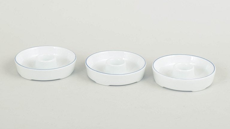 Grethe Meyer for Royal Copenhagen, Denmark. Set of three small Blue Line porcelain candlesticks with: Grethe Meyer for Royal Copenhagen, set of three small Blue Line candlesticks. Three small round candlesticks in white glazed porcelain with a simple blue line along the rim. The design forms part of