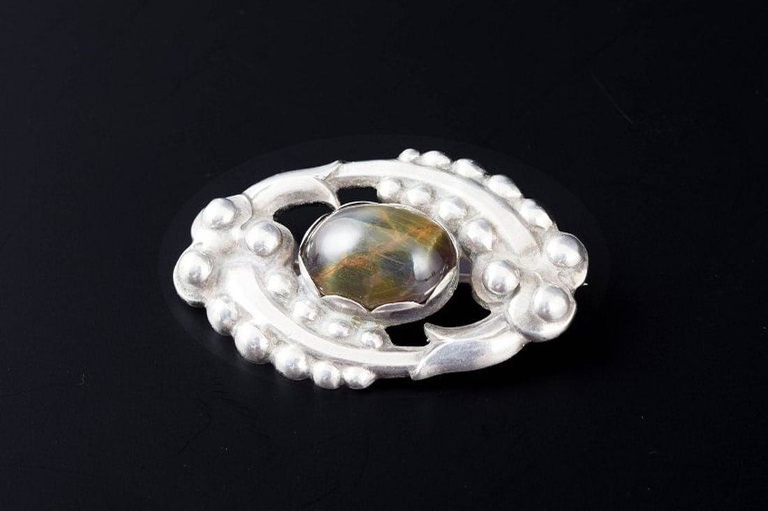 Kaj Bojesen, Randers. Oval silver brooch set with a cabochon-cut chrysoberyl catâ€™: Title:Kaj Bojesen, Randers. Oval silver brooch set with a cabochon-cut chrysoberyl catâ€™s eye. Circa 1920. Description:Kaj Bojesen, Randers Oval silver brooch set with a