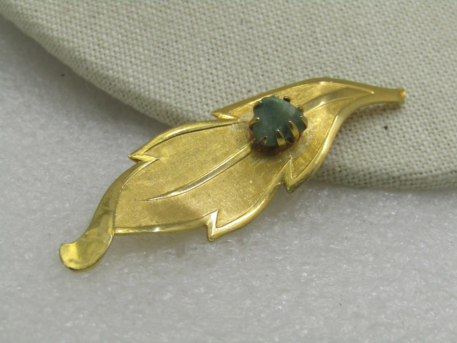 Vintage Gold Tone Green Agate Leaf Brooch, 2.75", 1960's: Vintage Gold Tone Green Agate Leaf Brooch, 2.75", 1960's. The leav is long with smooth edges and vein and textured leaf with a center triangular green agate nugget that is sitting on top of the brooch