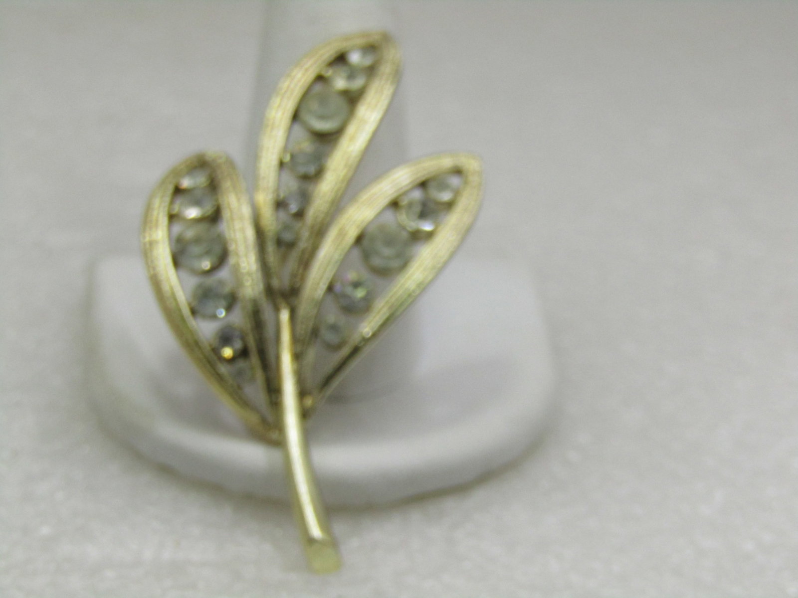Vintage Graduated Rhinestone Leaf Stem Brooch, 1960's, 2.5": Vintage Graduated Rhinestone Leaf Stem Brooch, 1960's, 2.5" by 1-3/8" wide. Three leaf blades with textured outline frame and open center with graduated clear rhinestones that range from 2.5mm to 5.5m