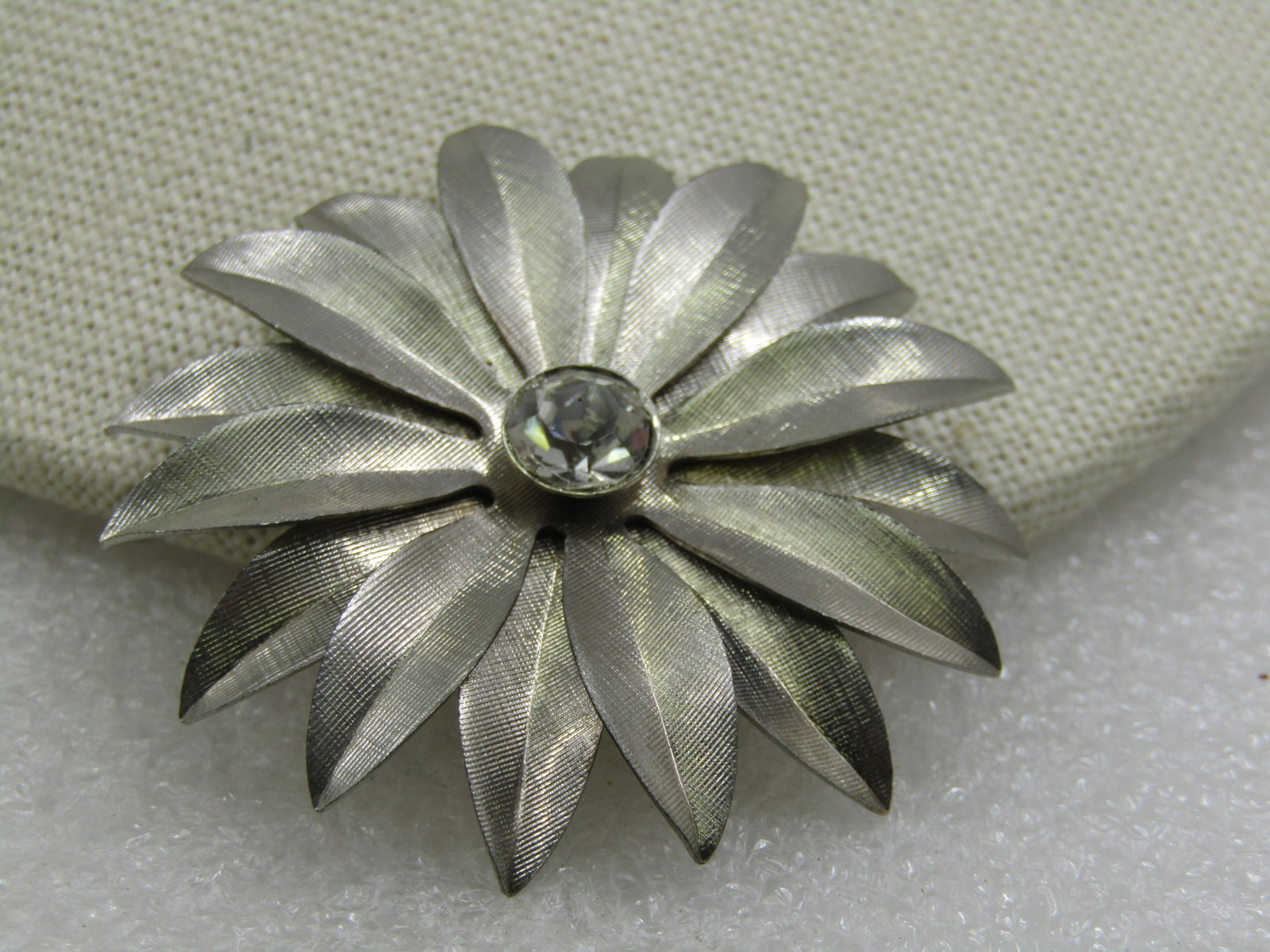 Vintage Silver Tone Blossom Brooch with Rhinestone 2": Vintage Silver Tone Blossom Brooch with Rhinestone 2". Two tiers of textured pionted leaves that curve upward from the center and then curve down at the edge with a raised appx. 8mm bezel-set rhinesto