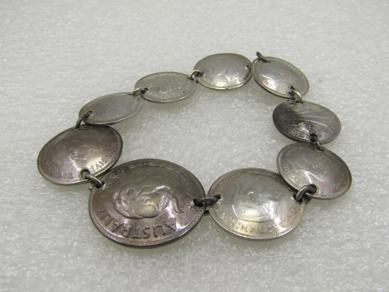 Vintage Silver Australian and UK Silver Coin Bracelet, 7", 1941-1943: Vintage Australian & UK Coin Bracelet, 7", 1941-1943, 9 Coins, the coins test as silver. Weight is appx. 20.43 gr.Domed coin some have back domed and some front. The center is Australian Shilling