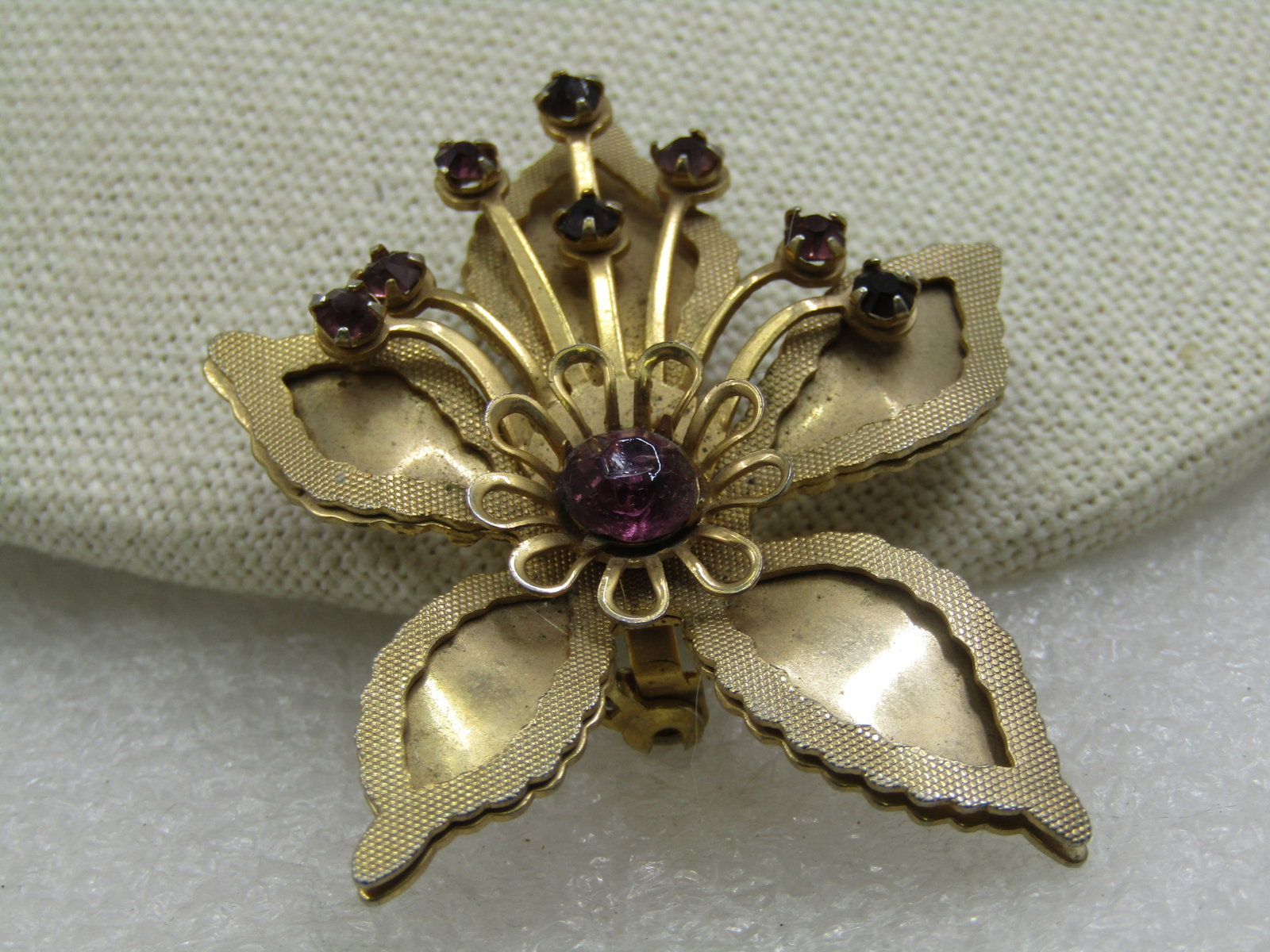 Vintage Orchid Brooch with Rhinestones, 1960's: Vintage Orchid Brooch with Rhinestones, 1960's. Purple rhinestones in the center and coming up from the center with a gold tone layered outline that is textured on the top of the leaf and smooth gold
