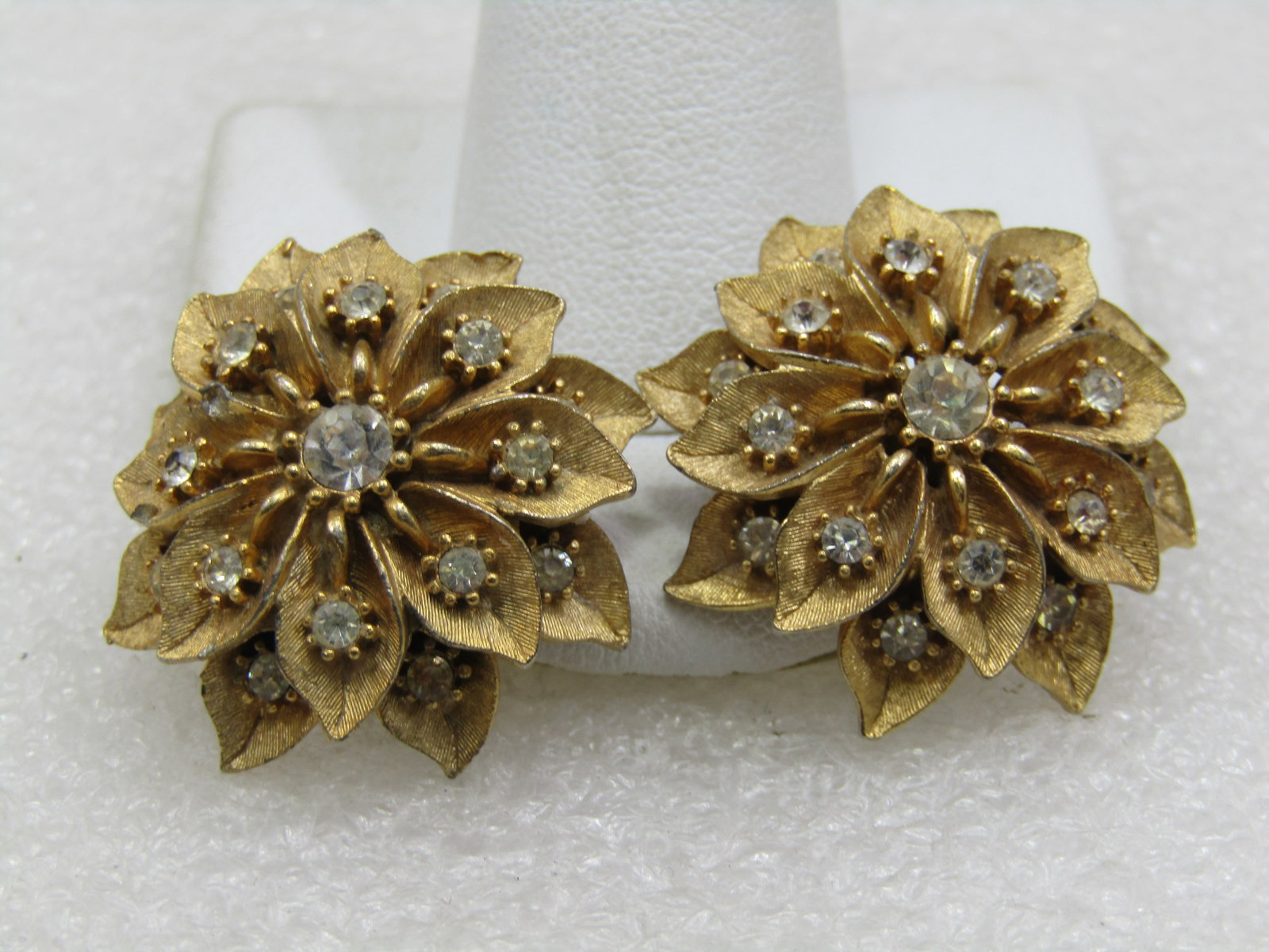 Vintage Gold Tone Rhinestone Blossom Earrings, Clip, 1960's: Vintage Gold Tone Rhinestone Blossom Earrings, Clip, 1960's. This is 1-1/8" across and a tiered design with a clear rhinestone in each leaf. Gold tone, satiny textured finish with a center rhinestone.