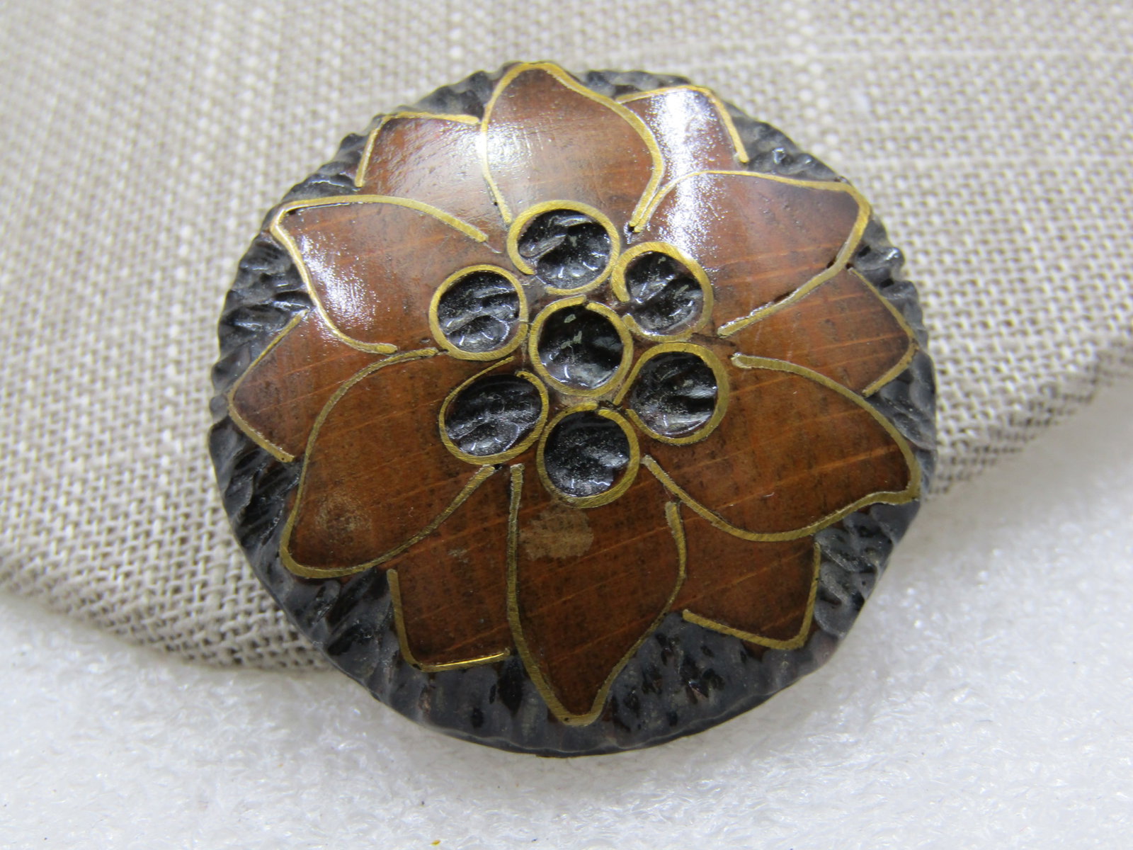 Vintage Inlaid Carved Wood Blossom Brooch , Mid-Century, 1.5": Vintage Inlaid Carved Wood Blossom Brooch , Mid-Century, 1.5" Round. Black textured wood background with a brown wooden blossom with the petals outlined in brass creating the inlaid look and round
