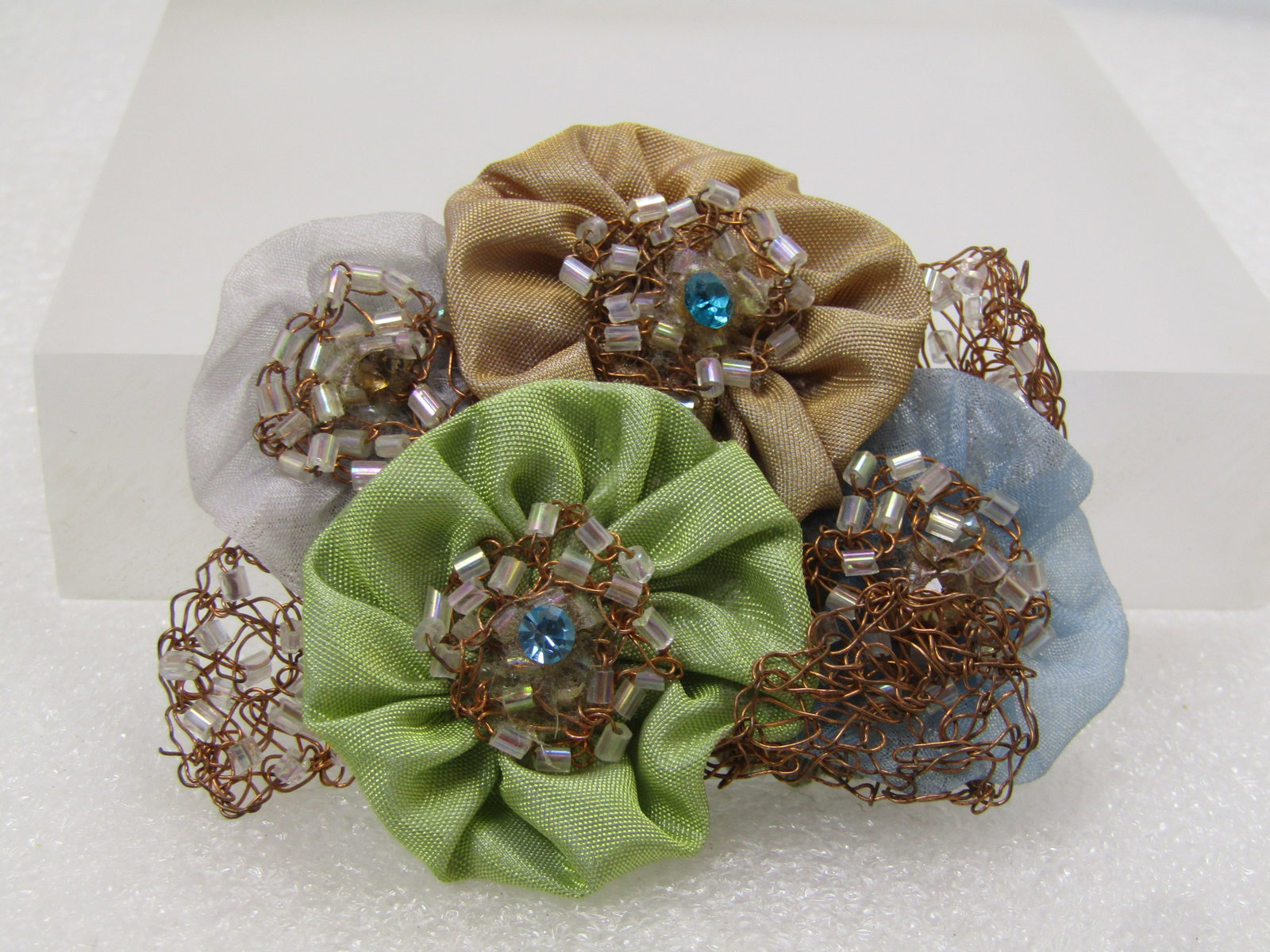 Vintage Hand Made Satin and Coppery Blossom Brooch, 1980's-1990's: Vintage Hand Made Satin and Coppery Blossom Brooch, 1980's-1990's. This is a mix of four satiny blossoms in blue, tan, white, and mint green with coiled copper thin wire to create the center of the fl