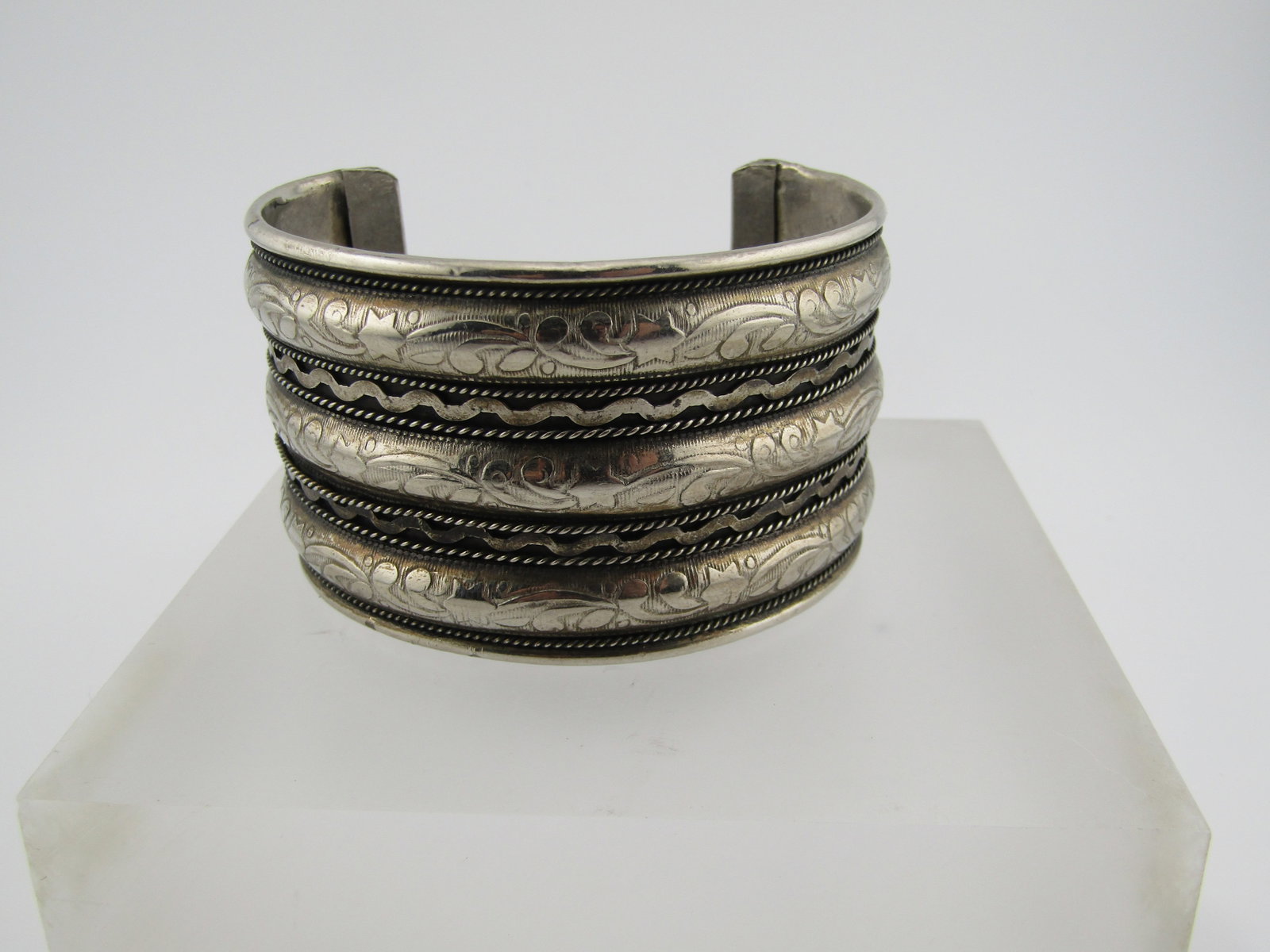 Silver Tone Wide Cuff Bracelet , 7.5", 1960's-1970's: Silver Tone Wide Cuff Bracelet , 7.5", 1960's-1970's. This bracelet has three domed floral/star and fine raised areas with two recessed with rope accents and a wavy design between the rope accents.
