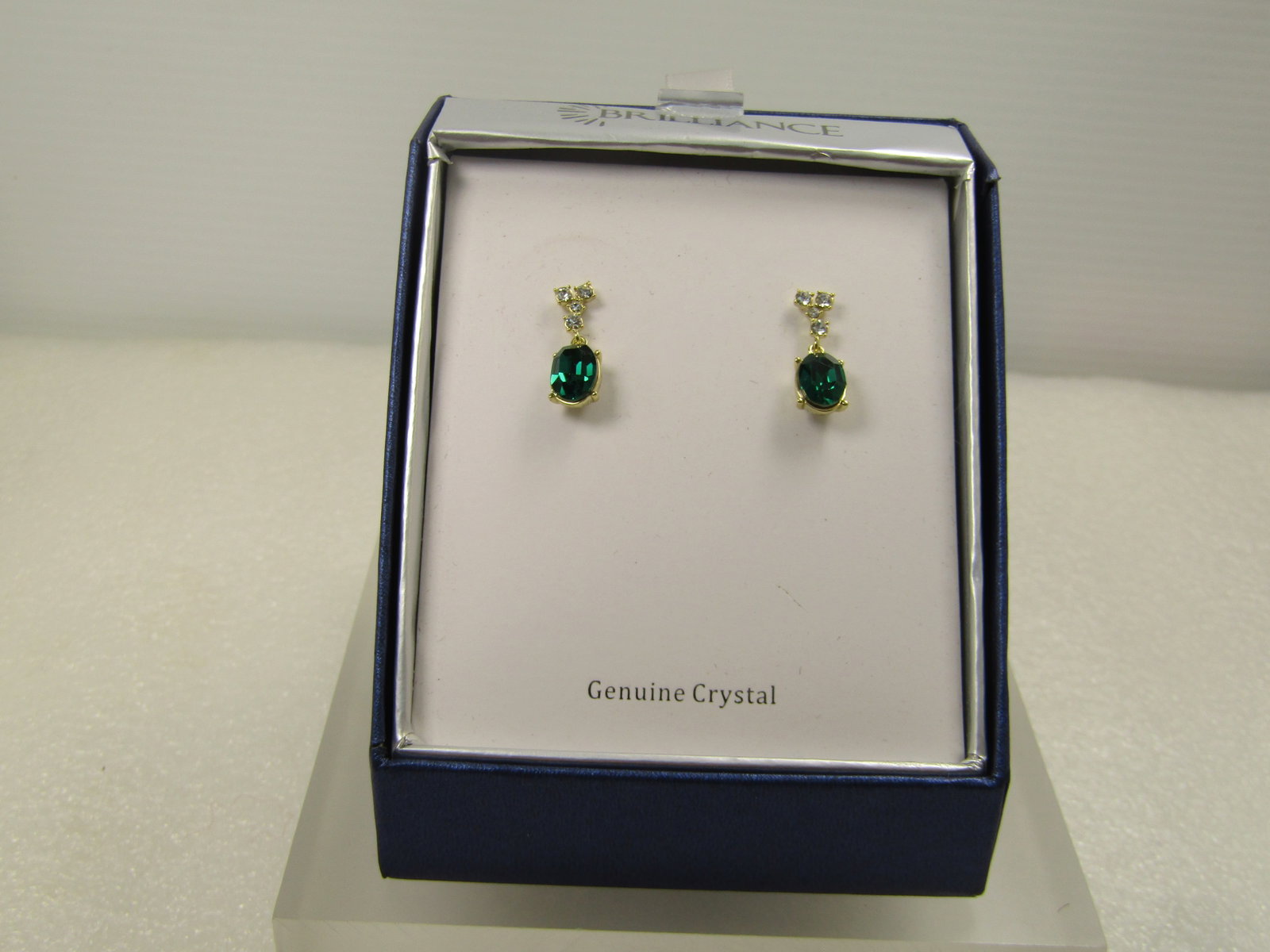 Emerald Green and Clear Crystal Drop Earrings by Brilliance, Original Box, Pierced, 1990's: Emerald Green and Clear Crystal Drop Earrings by Brilliance, Original Box, Pierced, 1990's. These have a stagered clear crystal stud from which an oval emerald green colored crystal drops. The