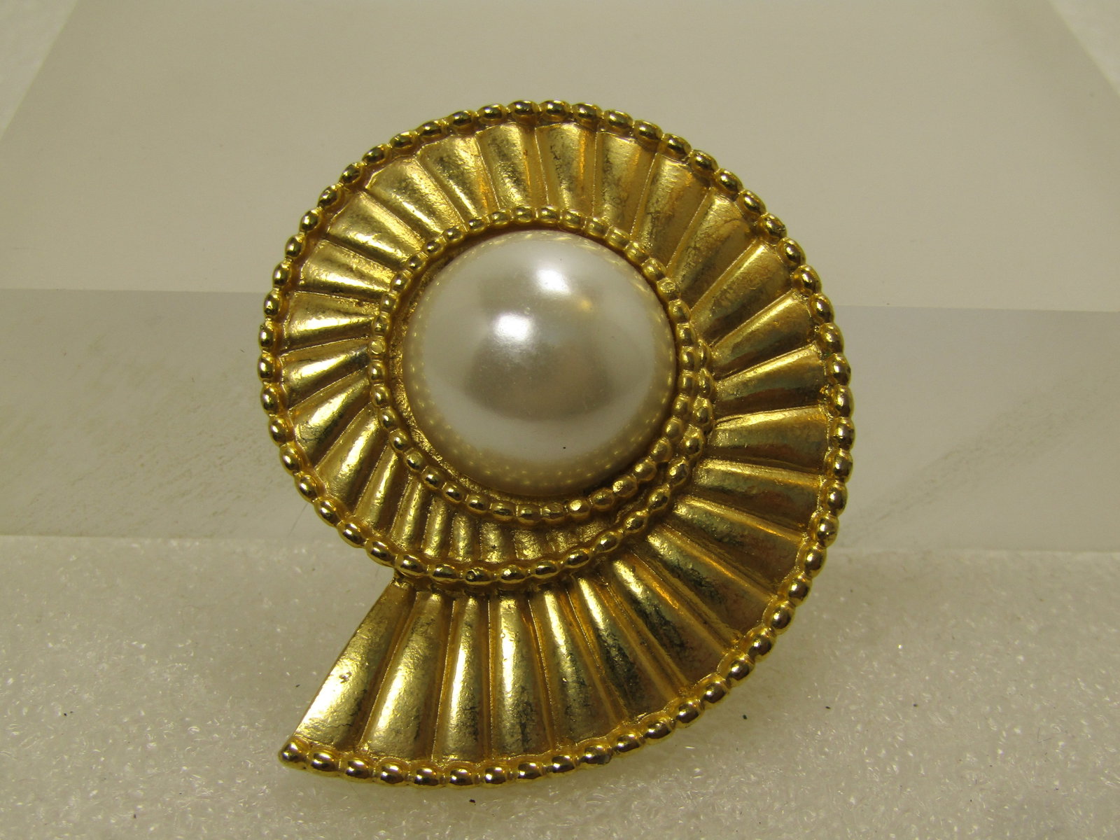 Vintage Faux Pearl Nautilus Brooch, 1980's: Vintage Faux Pearl Nautilus Brooch, 1980's. This has a domed half circle faux pearl that is appx. 3/4" round in the center with a ridged spiral with higher edges around the faux pearl creating the nau