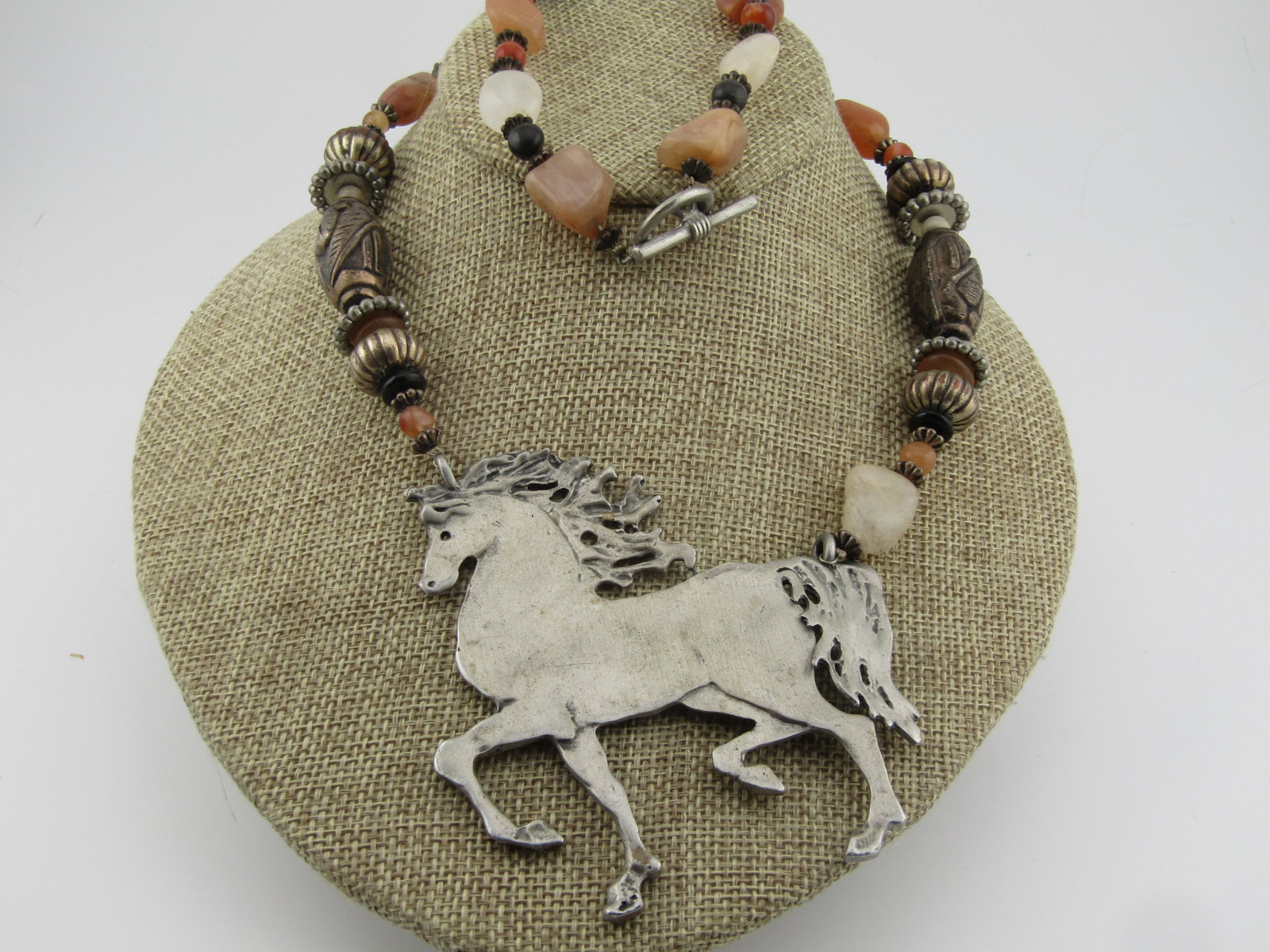 Large Horse Agate Beaded Necklace, Toggle Clasp, 24", 1980's-1990's: Large Horse Agate Beaded Necklace, Toggle Clasp, 24", 1980's-1990's. The horse is hand cut and 3" wide and 3.25" tall. It is made of a silver tone softer metal that can be bent if forced. It is best
