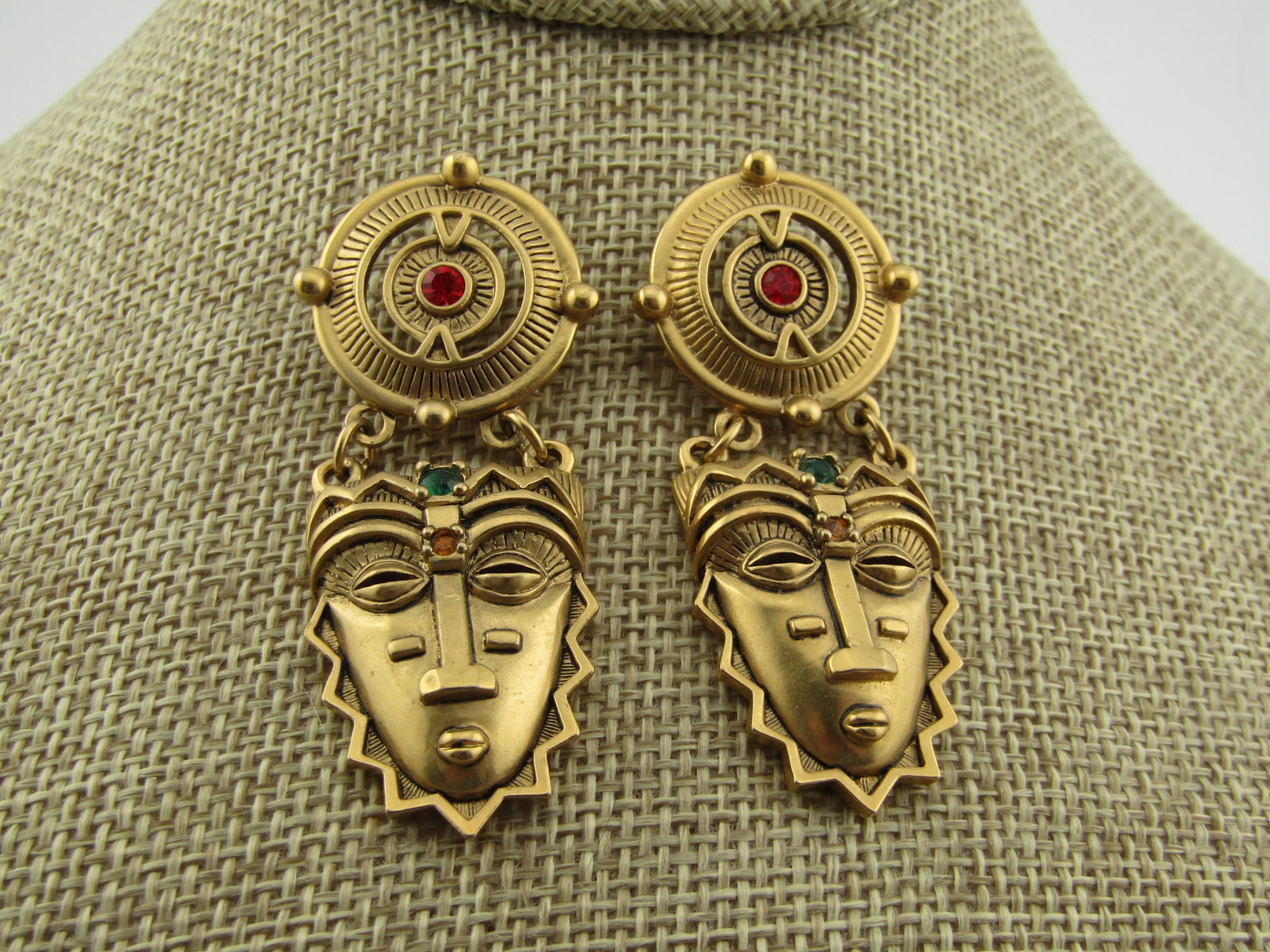Vintage Avon Tribal Mask Drop Earrings, 1993: Vintage Avon Tribal Mask Drop Earrings, 1993. These are gold tone with a matte-ish finish rather than totally bright and shiny. The top stud is an open wheel design with a center red rhinestone. That