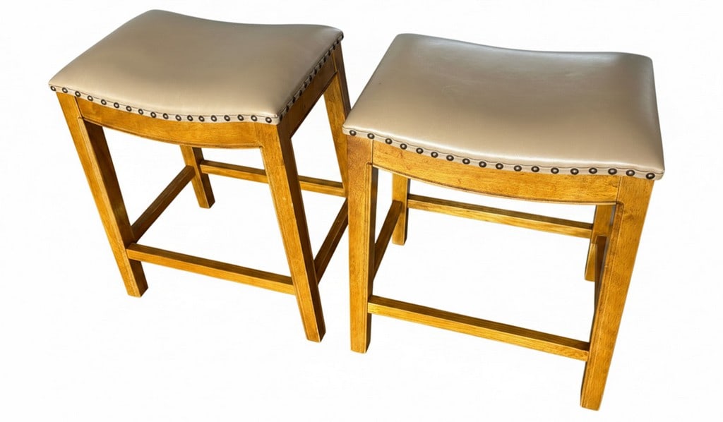 Pair of Wooden Counter Stools with Upholstered Seats: A pair of wooden counter stools featuring light brown upholstered seats with decorative nailhead trim. The stools have a simple, tapering leg design with stretchers for stability. The wood grain is