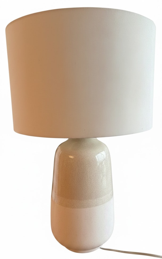 Contemporary Ceramic Table Lamp: A contemporary ceramic table lamp featuring a two-tone speckled glaze in off-white and beige on the base, topped with a drum-shaped fabric shade. The design is modern minimalist, suitable for various