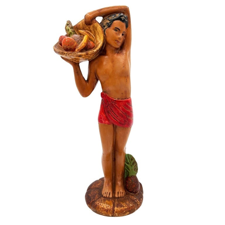 Mid-Century Native Boy w/ Fruit Offering Ceramic Hand Painted Sculpture: Original post-war ceramic Hawaiian native boy with fruit offering and flowers made from lightweight plaster and painted in vibrant tropical colors. It depicts a young Native Hawaiian boy with a Lei in