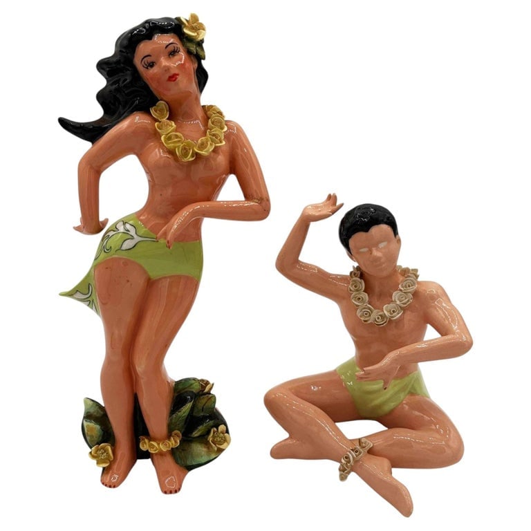 Mid-Century Hawaiian Hand Painted Hula Girl and Surfer Male Ceramic Statue, Pair: This pair of vintage mid-century ceramic figurines depicts a stylized Polynesian man and woman. Hand-painted with a glossy finish, the man and woman both in mid celebration, both adorned in traditiona