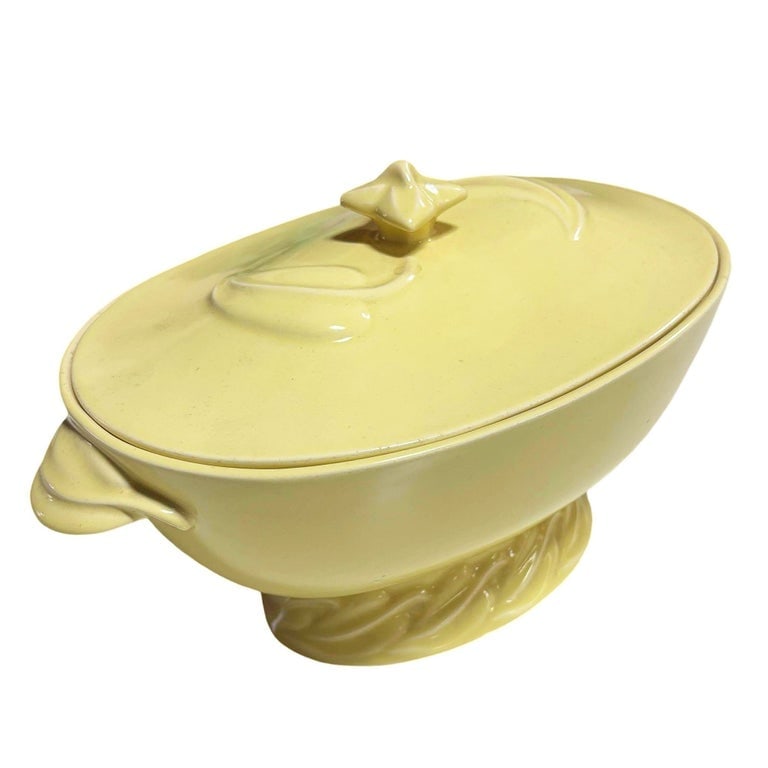 Mid-Century California Pottery Yellow Casserole Dish w/ Lid by Vernon Kilns: Vibrant Mid-Century Modern ceramic covered tureen, featuring a striking buttery yellow glaze by Vernon Kilns. This oval-shaped serving piece sits on an integrated, pedestal foot adorned with a dynamic