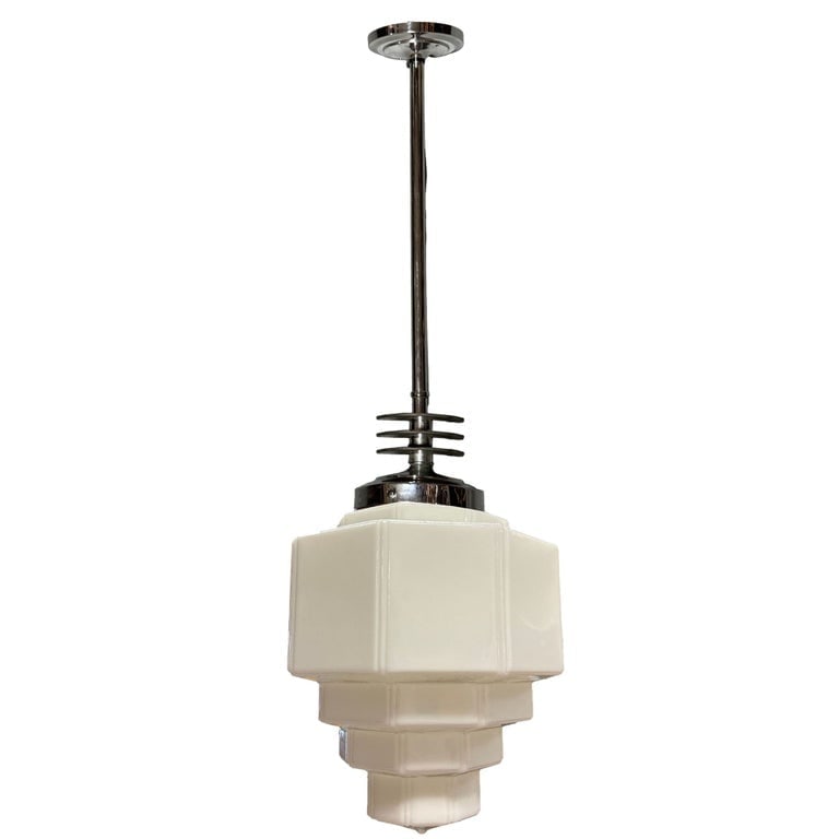 Art Deco Chrome Streamline Pendant Light w/ Stepped Milk Glass Shade: 1930s Art Deco pendant light featuring a stepped milk glass shade. It is paired with a Streamline Art Deco pendant lamp showcases chromed finish body with 3 black enameled Saturn rings along the neck.