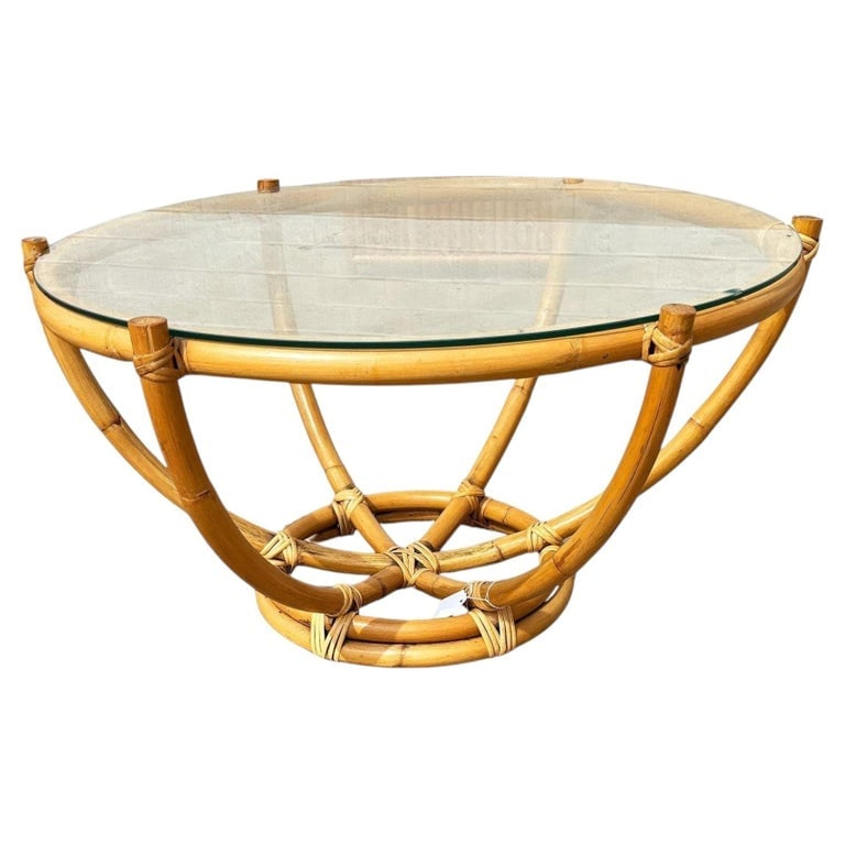 Restored Mid-century Six-Pole Rattan Coffee Table W/ Floating Glass Top: This beautifully restored coastal six-pole rattan coffee table with stacked rattan round base. The six rattan poles organically branch outward to a circular top made of a single piece of bent rattan. 
