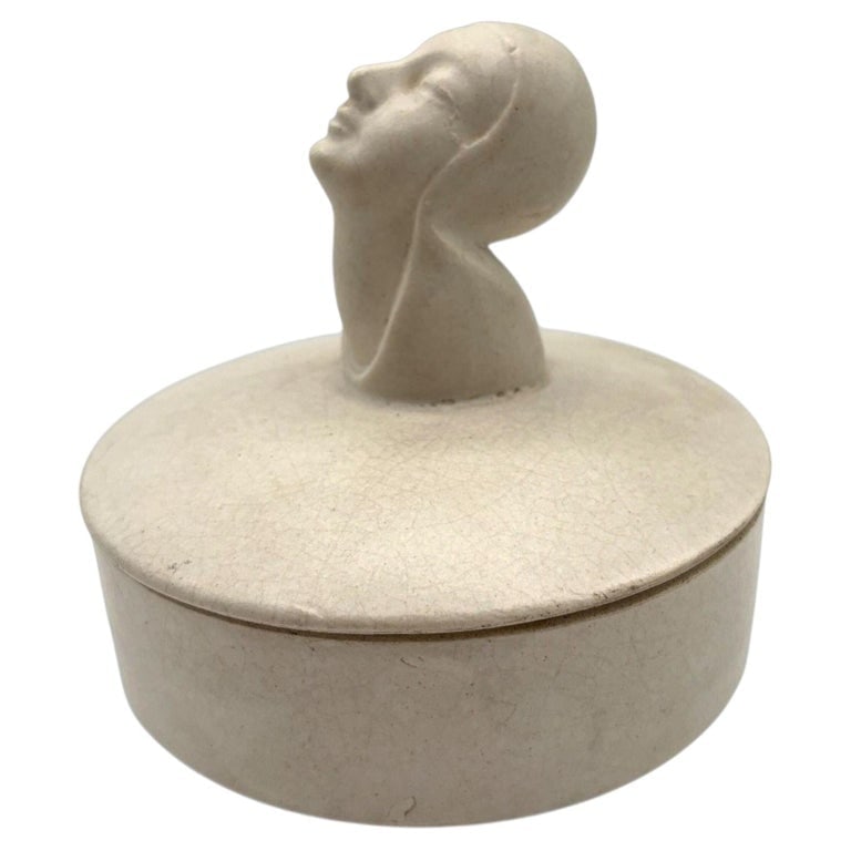 Mid-century Gray Earthenware Ceramic Vanity Powder Box w/ Female Bust Handle: A serene 1930s Art Deco powder box featuring a sculpted woman with her head gently tilted upward and eyes closed, embodying the calm, modern femininity celebrated in the eras design. Her tranquil expr
