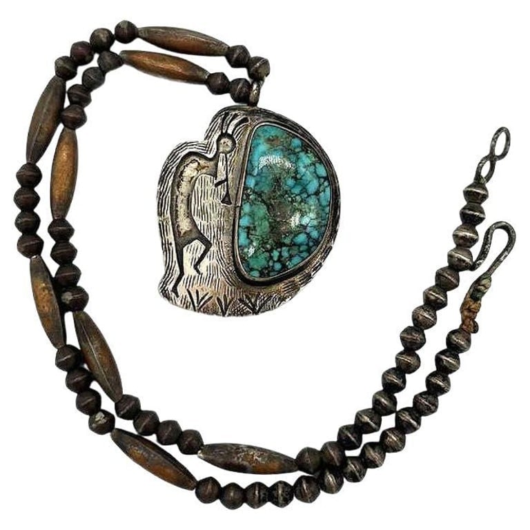 South Western Navajo Kokopelli Sterling Silver Necklace w/ Large Turquoise Stone: A Navajo Sterling Silver Necklace with a Turquoise stone, this beautiful necklace depicts Kokopelli, a prehistoric fertility deity rooted in Native American culture, is often depicted as a hunchbacked