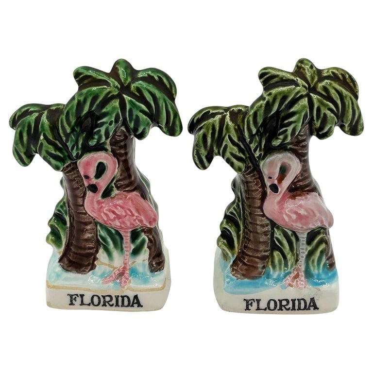 Mid-century Florida Flamingo Ceramic Salt and Pepper Shaker Set: Mid-century pink and green ceramic flamingo tabletop salt and pepper shaker set. The set features two beautifully detailed pink flamingos, each on a lush palm tree beach, with the word "Florida"