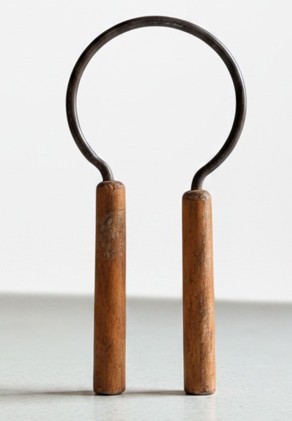 Vintage Cast Iron Jar Opener with Wooden Handles: A vintage cast iron jar opener, likely dating from the mid-20th century, featuring a classic openwork design and two wooden handles for safe handling. The metal shows a natural patina consistent with