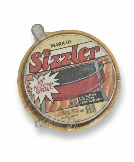 Vintage Mark III Sizzler 13" Adjustable Grill in Original Packaging: This vintage Mark III Sizzler 13" Adjustable Grill is new in its original, unopened plastic packaging. The grill features a red base and adjustable grilling surface as depicted on the packaging. The