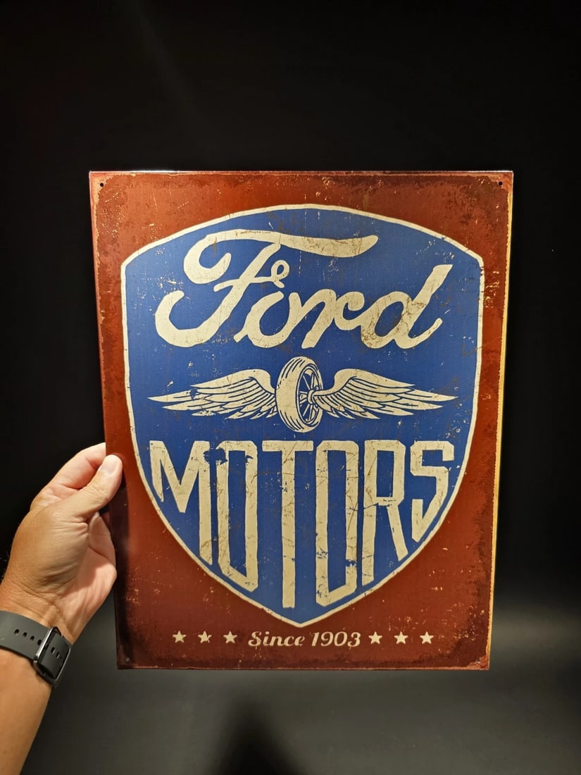 16" Metal Vintage Style Ford Motors Sign: 16" x 12 1/2" Such a neat reproduction metal vintage style Ford Motors sign featuring an early version of the company's logo. The sign has a red background with a blue shield in the center. The shield