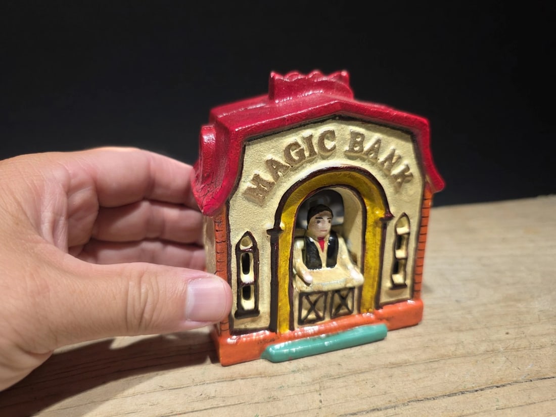 Cast Iron Magic Coin Bank: 4" Long x 4 1/8" High Great reproduction cast iron coin bank. This piece was made to look just like an antique, but is actually new. Great aged paint. Reserve: $24.00 Shipping: Domestic: Flat-rate of