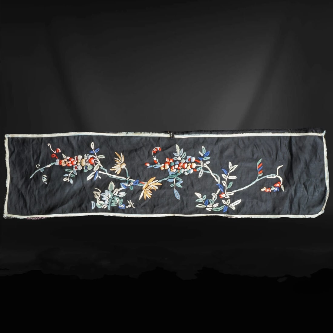 Chinese Black Silk Embroidered Panel c 1900: Title:Chinese Black Silk Embroidered Panel c 1900 Size:36” long x 10” tall. Description:A colorful, hand-embroidered silk panel that depicts floral designs of wisteria and chrysanthemums. 