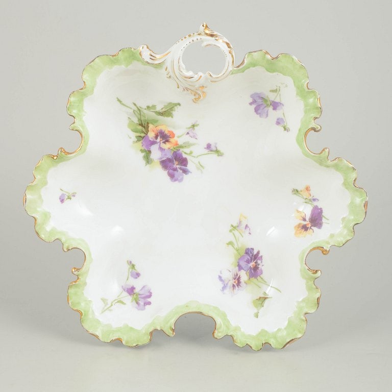 Rosenthal, Germany. Gold decorated floral bowl in porcelain with a scalloped edge and pierced: Rosenthal, gold decorated floral bowl. Decorative porcelain bowl with a scalloped edge and pierced handle, adorned with hand-painted floral motifs in purple and green tones and gilt detailing,