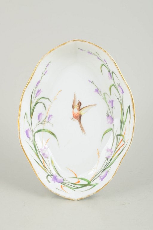 Royal Copenhagen, Denmark. Oval porcelain dish with bird motif in purple and green tones. Mid-19th: Royal Copenhagen, oval dish with bird motif. Antique oval dish in hand-painted porcelain featuring a central bird motif surrounded by floral decoration in purple and green tones, finished with a gilde