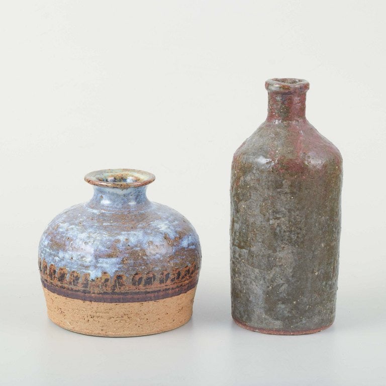 European studio potters. Two small stoneware vases. 1960s-1970s.: European Studio Potters Two stoneware vases, one with a wide body and flared neck, decorated with blue and brown glaze over a chamotte-like base, the other cylindrical with a narrow neck and rustic br