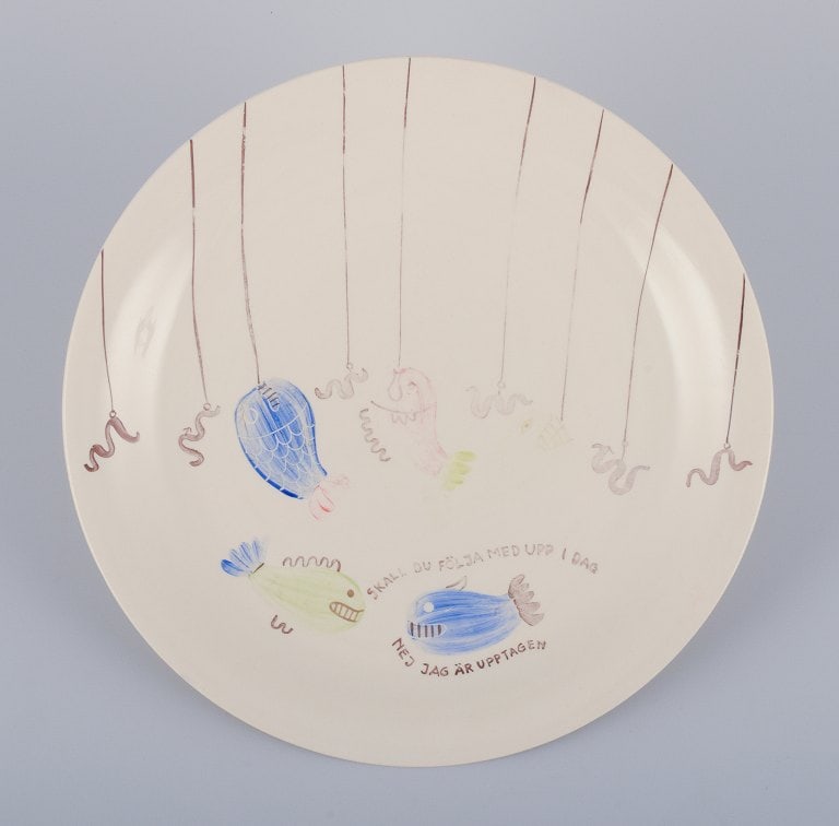 Stig Lindberg for Gustavsberg. "Löja" plate. Hand-painted with a fish motif. Satirical: Stig Lindberg for Gustavsberg. "Löja" plate. Hand-painted with a fish motif. Satirical illustration with Swedish text. From the 1950s. In good condition with some slight wear to the paint and a s