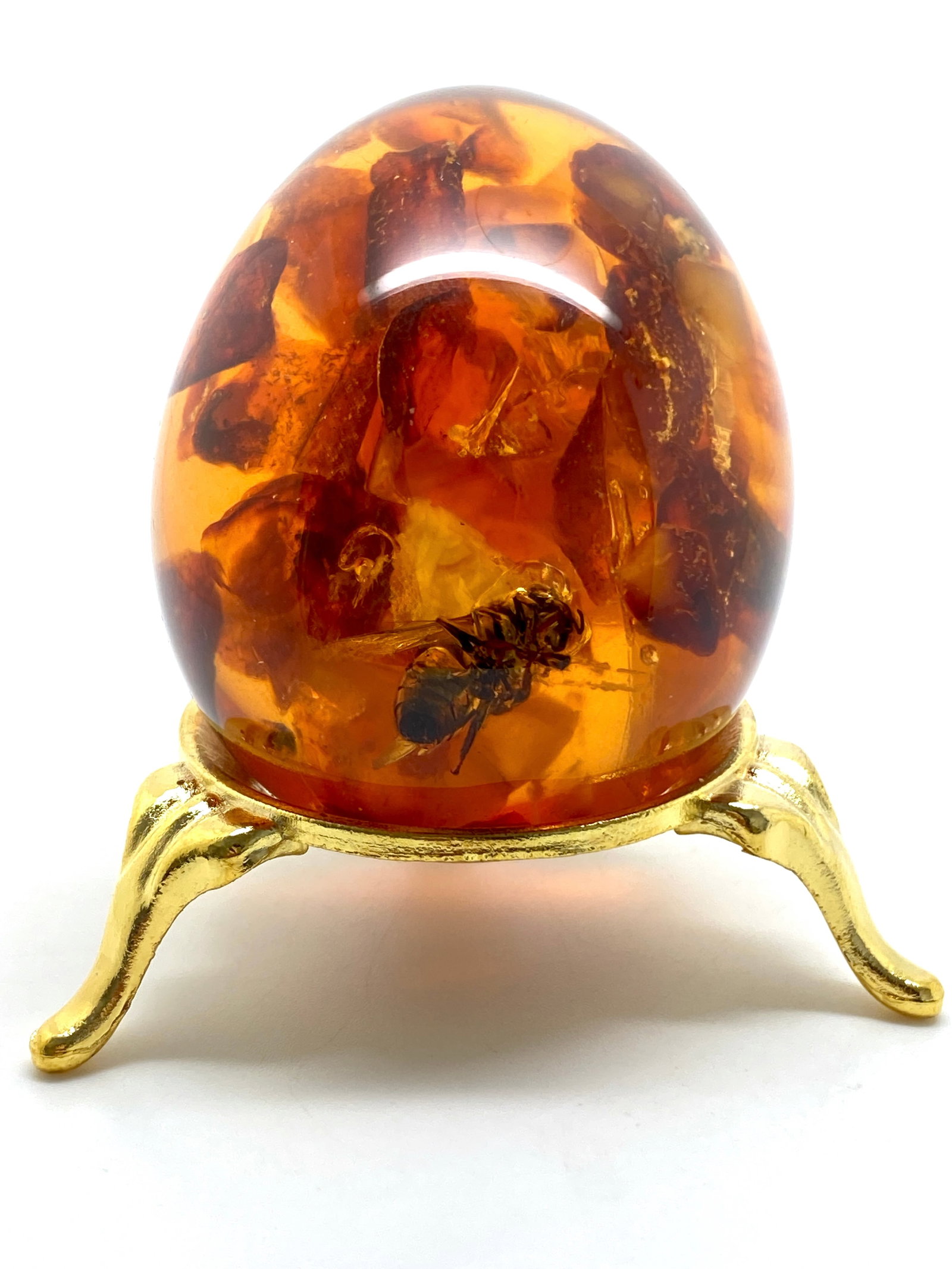 Remarkable Amber Egg on a pedestal with insect inclusion: Title:Remarkable Amber Egg on a pedestal with insect inclusion Metal:None Gemstone:Amber Weight:71.2 g Size:Size: 56.7 x 45.0 x 45.0 mm Size: 2.232 x 1.772 x 1.772 inches Made of:(Reconstituted Amber