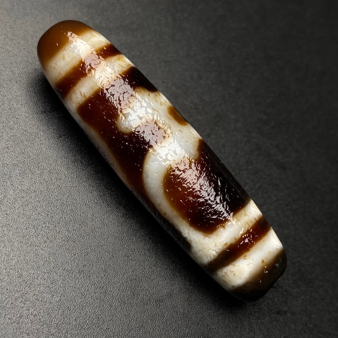 Old Tibetan DZI Agate Pendant: Title: Old Tibetan DZI Agate Pendant Origin: Chinese Date/Period: After1910 Materials: DZI Agate Dimensions: 47x12(mm) 1.85x0.47(inches) Weight 0.03 lbs/11.9g Reserve: $120.00 Shipping: Domestic: Ship