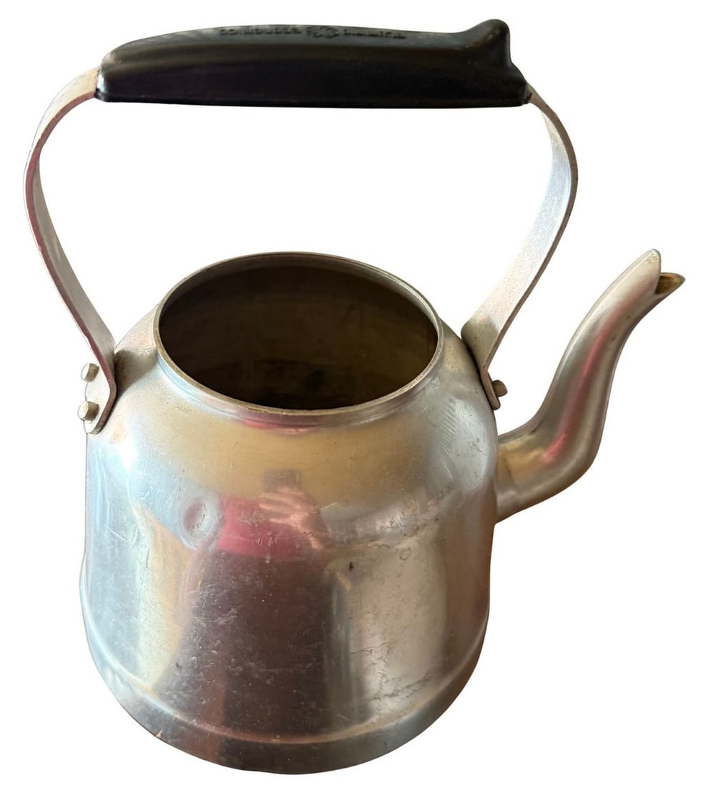 Vintage Aluminum Teakettle with Black Bakelite Handle: A vintage aluminum teakettle, likely dating from the mid-20th century, featuring a classic rounded body and a prominent black Bakelite handle. The kettle has a traditional spout and an open top. The