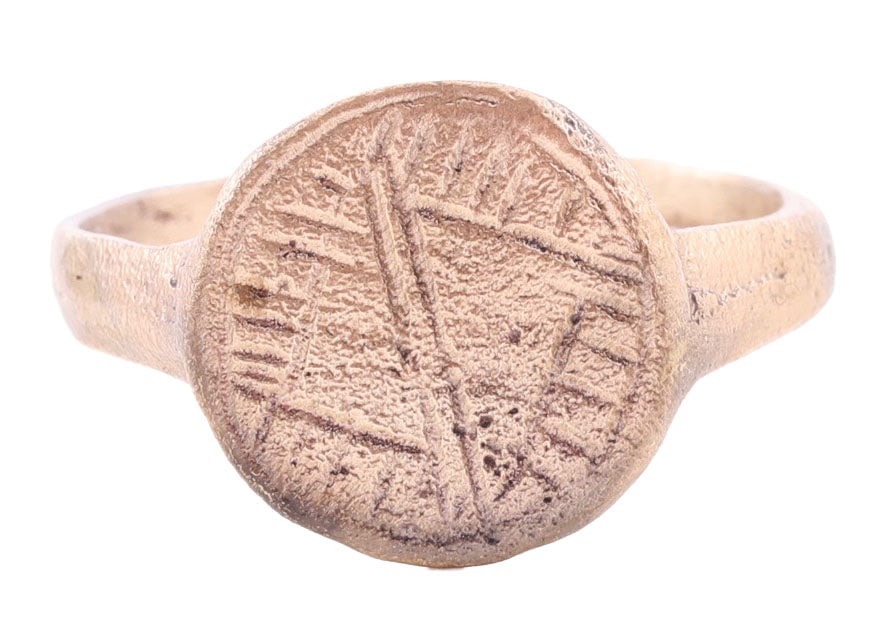 ROMAN MAN’S RING C.100-400 AD, SIZE 9 1/2: Gilt bronze, size 9 1/2. 1.9mm oval, rounded face band flaring to the ridged shoulders. Bordered circular bezel cut with a double transverse line bisecting a diamond on a hatched field. Undoubtedly wi