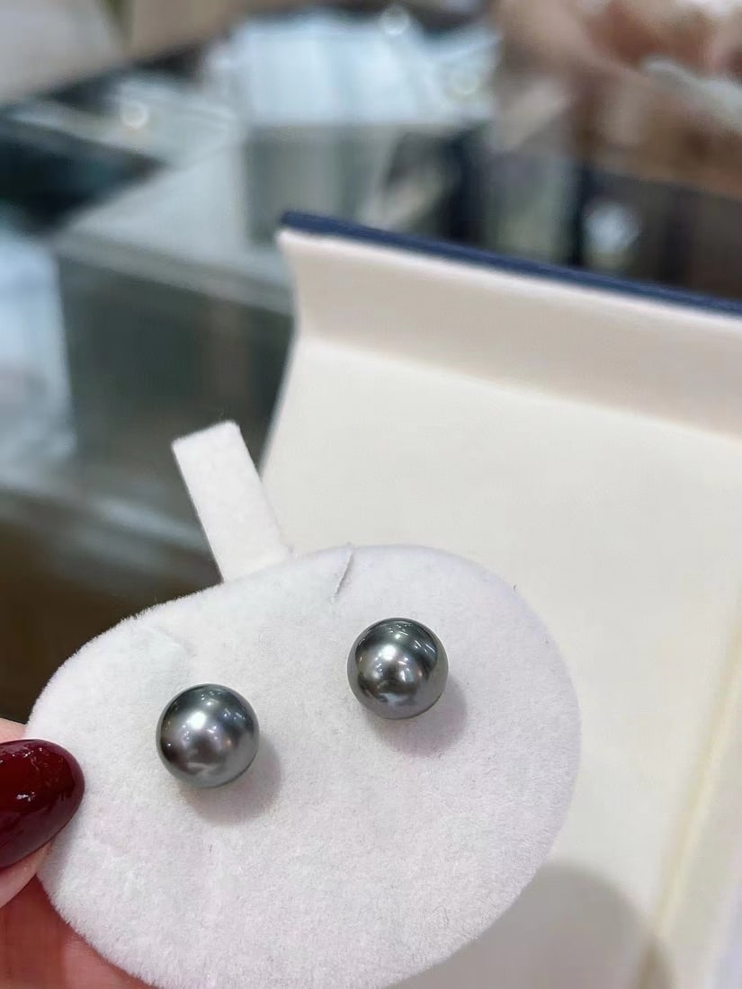 18K White Gold Perfectly Round Slightly Blemished Tahitian Black Pearl Earrings: Title: 18K White Gold Perfectly Round Slightly Blemished Tahitian Black Pearl Earrings Description: These earrings are crafted in 18K white gold, featuring perfectly round 10-11mm Tahitian black