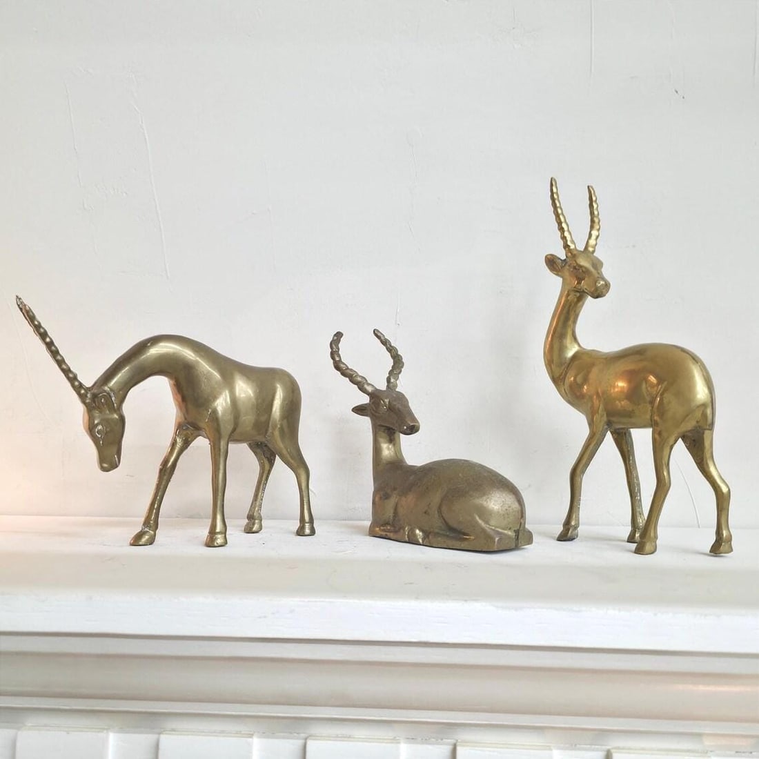 Vintage Brass Gazelles Sculptures Shelf Decor Antelope Set of 3 MCM Figurines Hollywood Regency: A sculptural set of 3 vintage brass antelope or gazelle figures with warm aged patina, made for shelf styling, consoles, bookcases, and collected interiors. This brass animal trio has the kind of quie