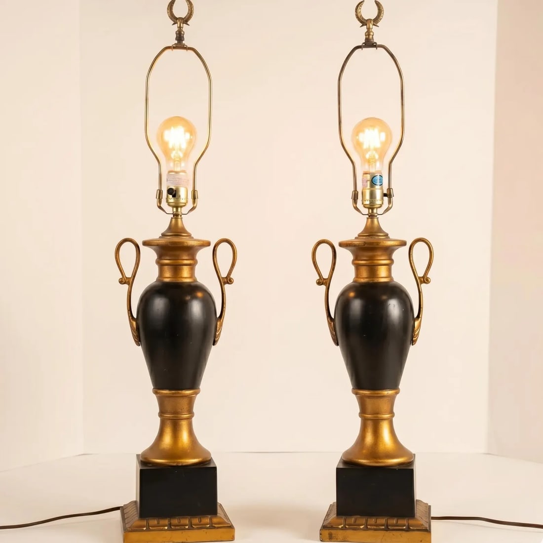 Neoclassical Black Gold Gilt Table Lamps Pair Hollywood Regency Urn Trophy Style: Hollywood Regency Pair Table Lamps with Original black finish and gold gilt detailing and the original finials. Tall console lamps for entryway, made by LampCrafters based in Lexington NC. These were 