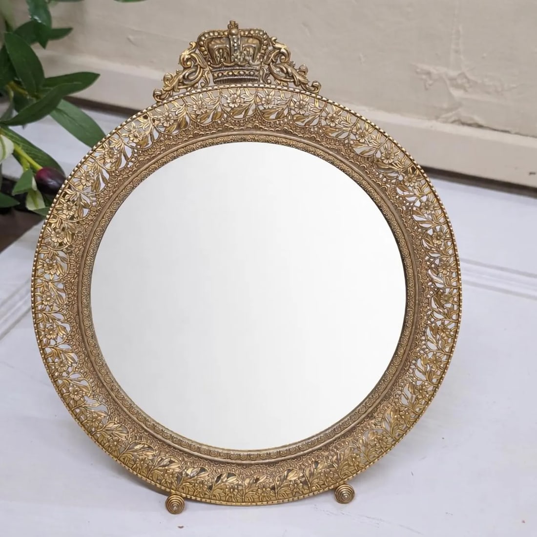Gilt Brass Vanity Mirror, Crown Crest Filigree Frame, Tabletop Easel Stand: Vintage gilt metal vanity mirror w crown crest + pierced floral border. 9.5”H x 8”W tabletop easel. Ships free, packed pro. A small, decorative tabletop vanity mirror with a pierced floral