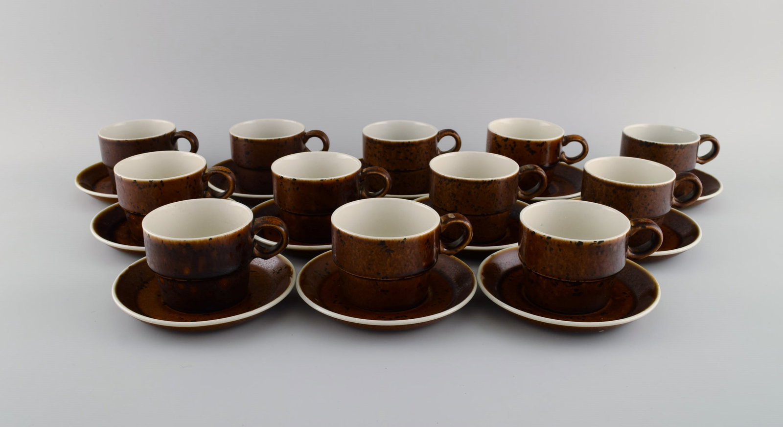 Stig Lindberg for Gustavsberg. Twelve Coq coffee cups with saucers in glazed stoneware. Beautiful: Stig Lindberg for Gustavsberg. Twelve Coq coffee cups with saucers in glazed stoneware. Beautiful glaze in brown shades. Swedish design, 1960s. The cup measures: 7.5 x 6 cm. Saucer diameter: 13 cm. In