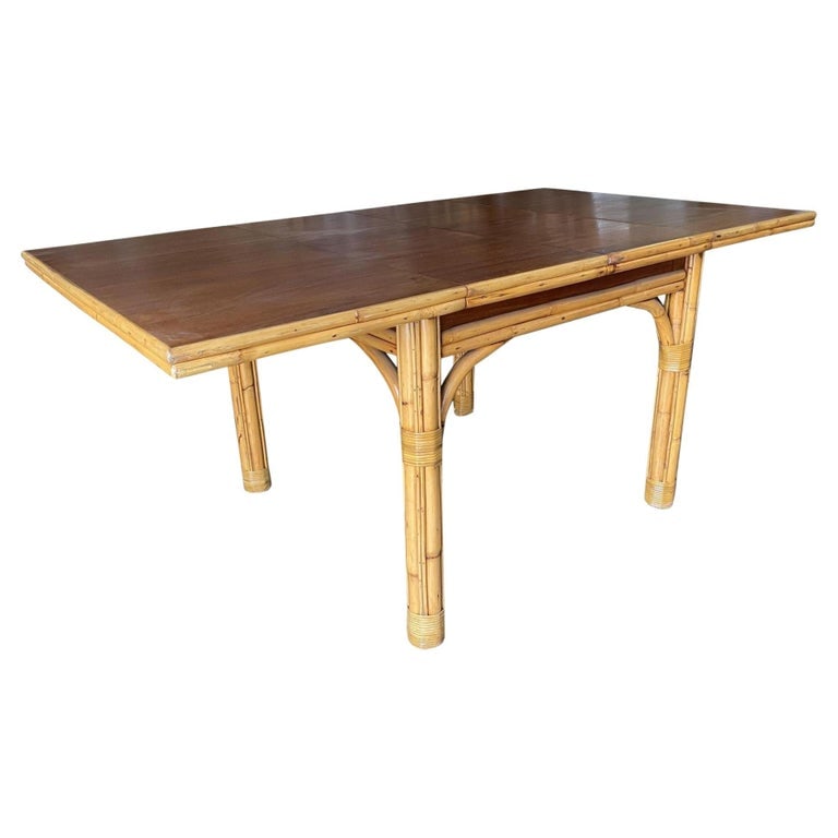Mid Century Rattan and Mahogany Expandable Dining Table w/ Leaves: This beautifully restored Paul Frankl-inspired Mid-century six-eight person rattan dining table has with pole rattan base and a solid mahogany table. The large rattan dining table comes with three pol
